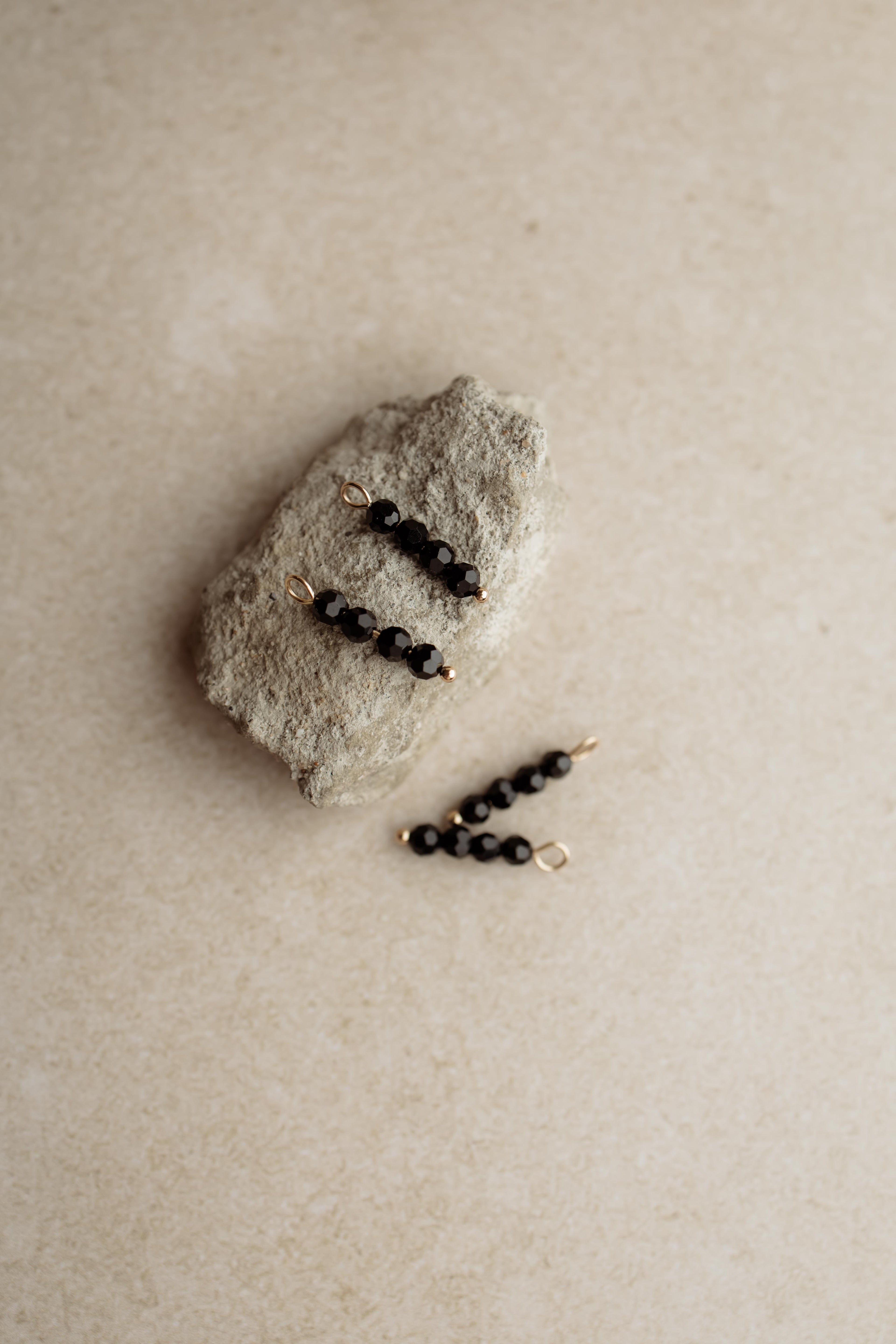 Zwarte bedeltjes met kralen voor aan oorringen of creolen.