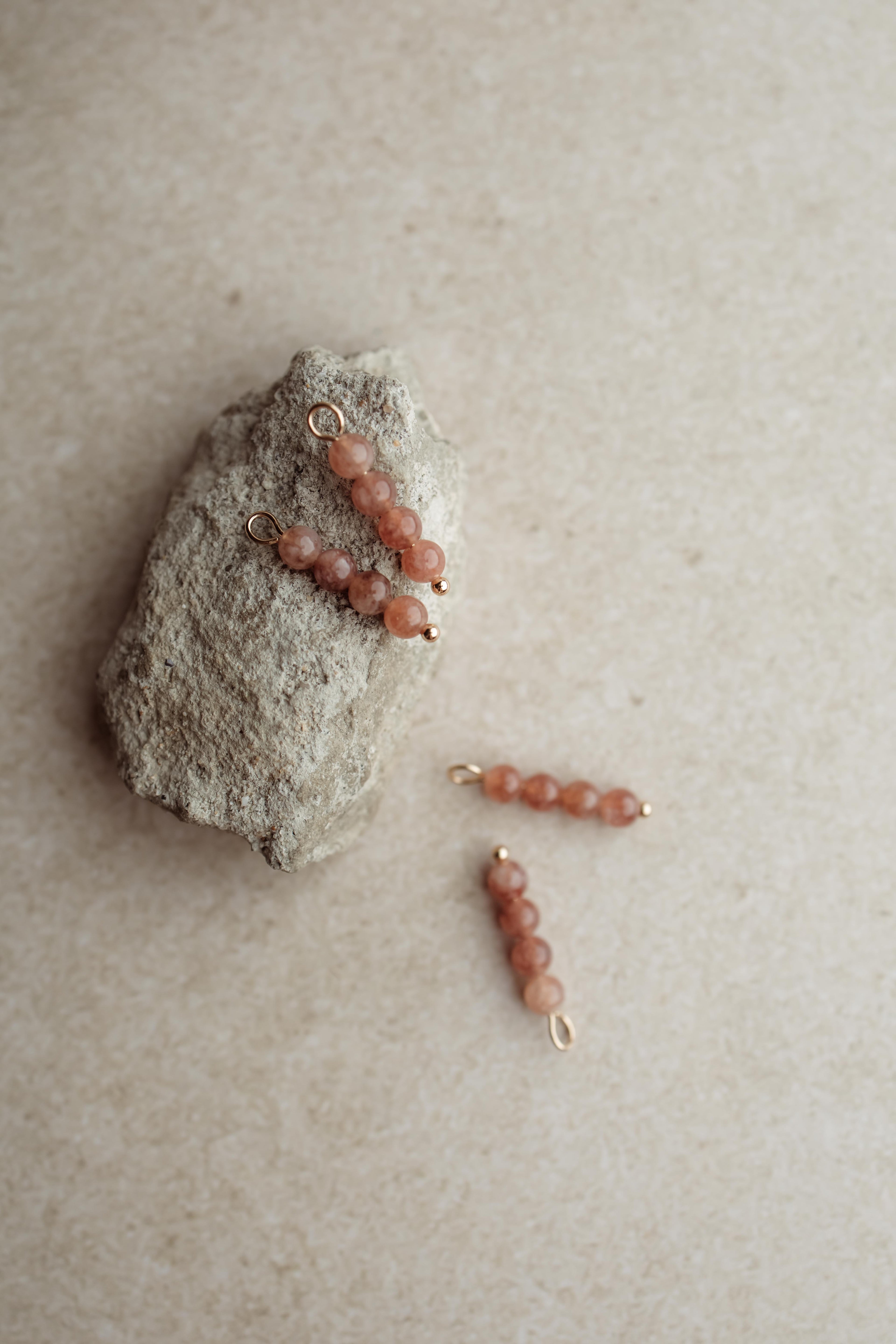 Bedel met goudkleurige details en warme kraaltjes. Hang ze aan de oorringen of creolen uit de collectie van Pure Black Styling.