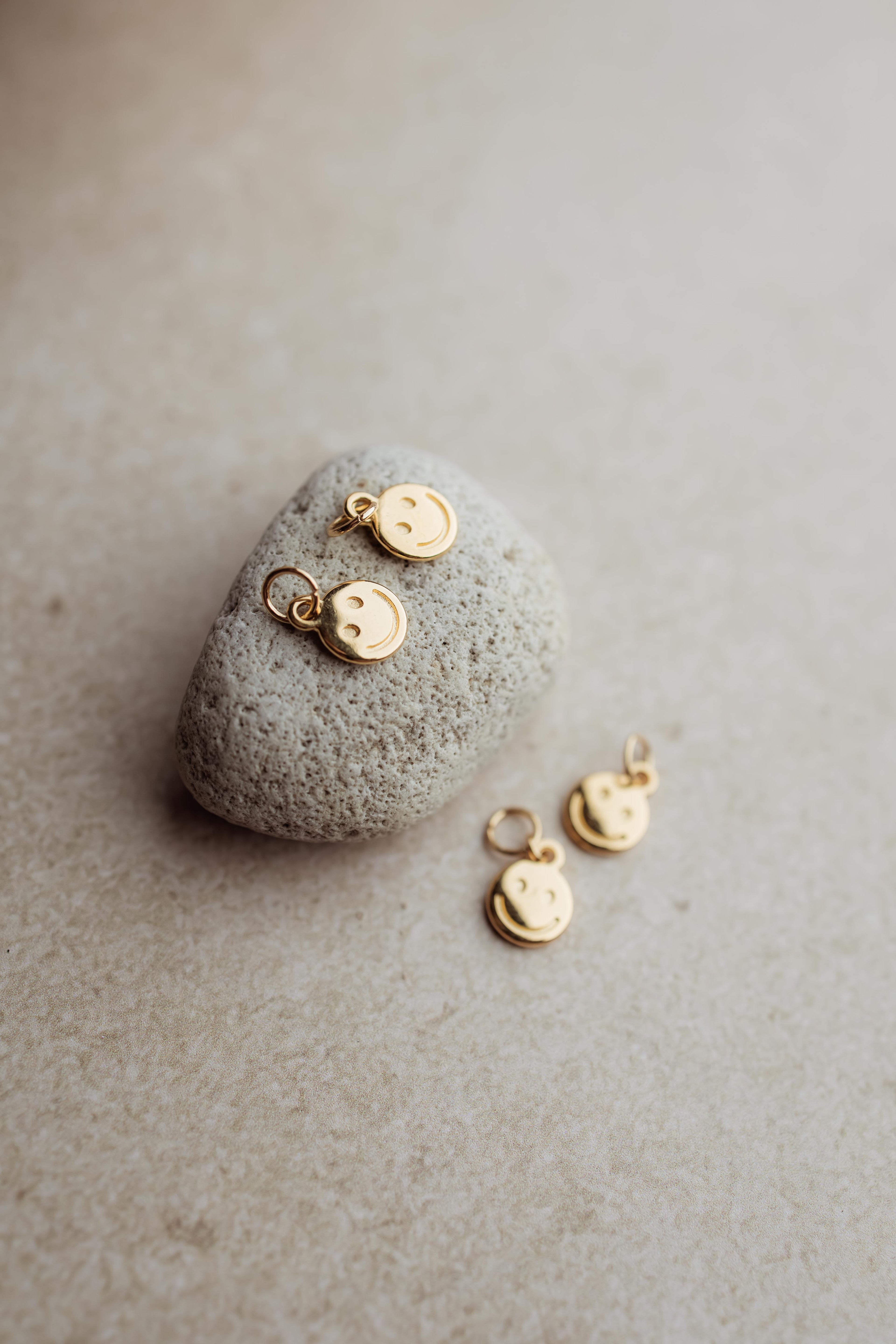 Gouden smiley bedel voor aan oorbellen en hangers.