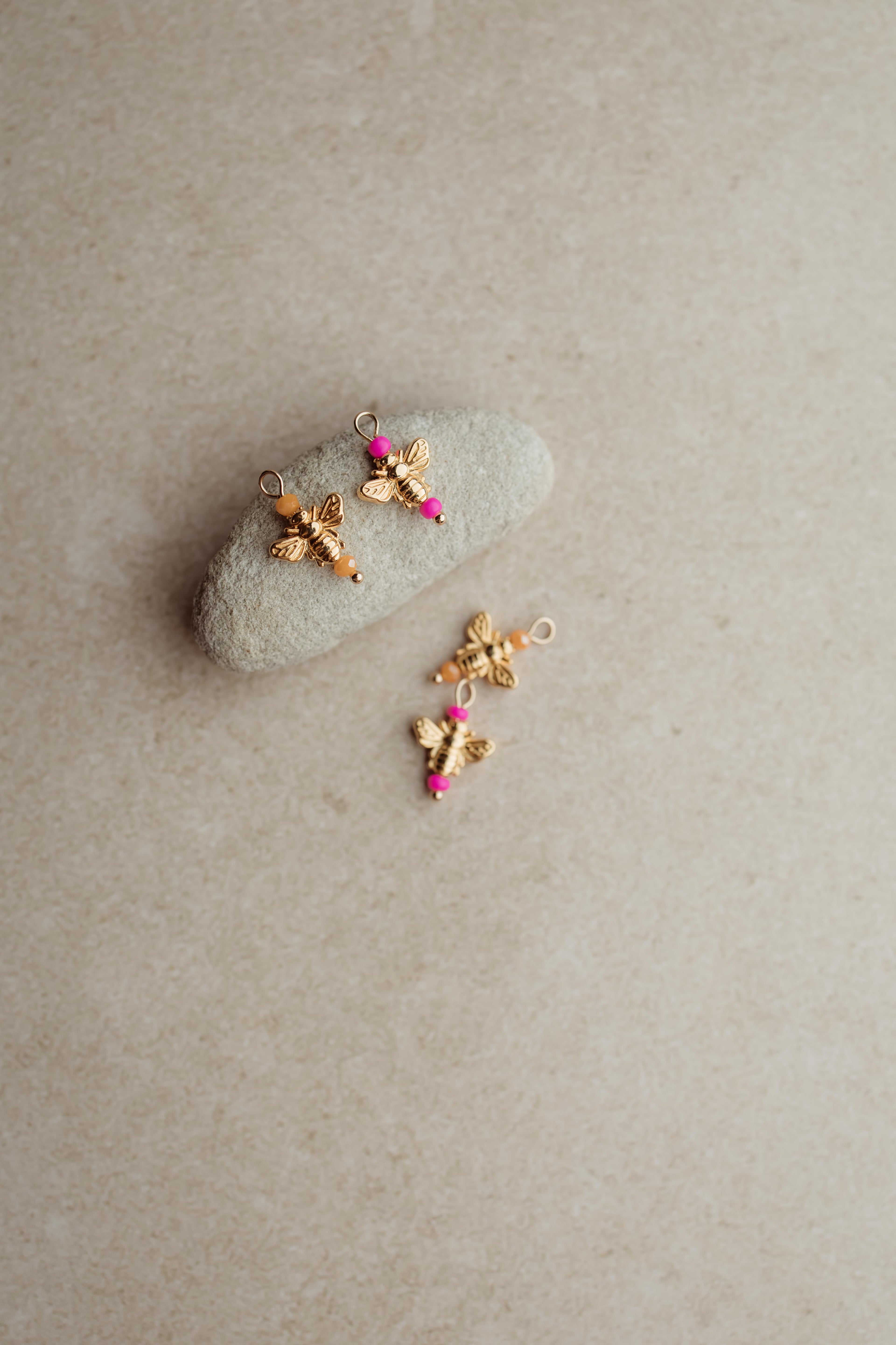 Bedeltje met bijtjes, verkrijgbaar in roze of oranje kraaltjes.