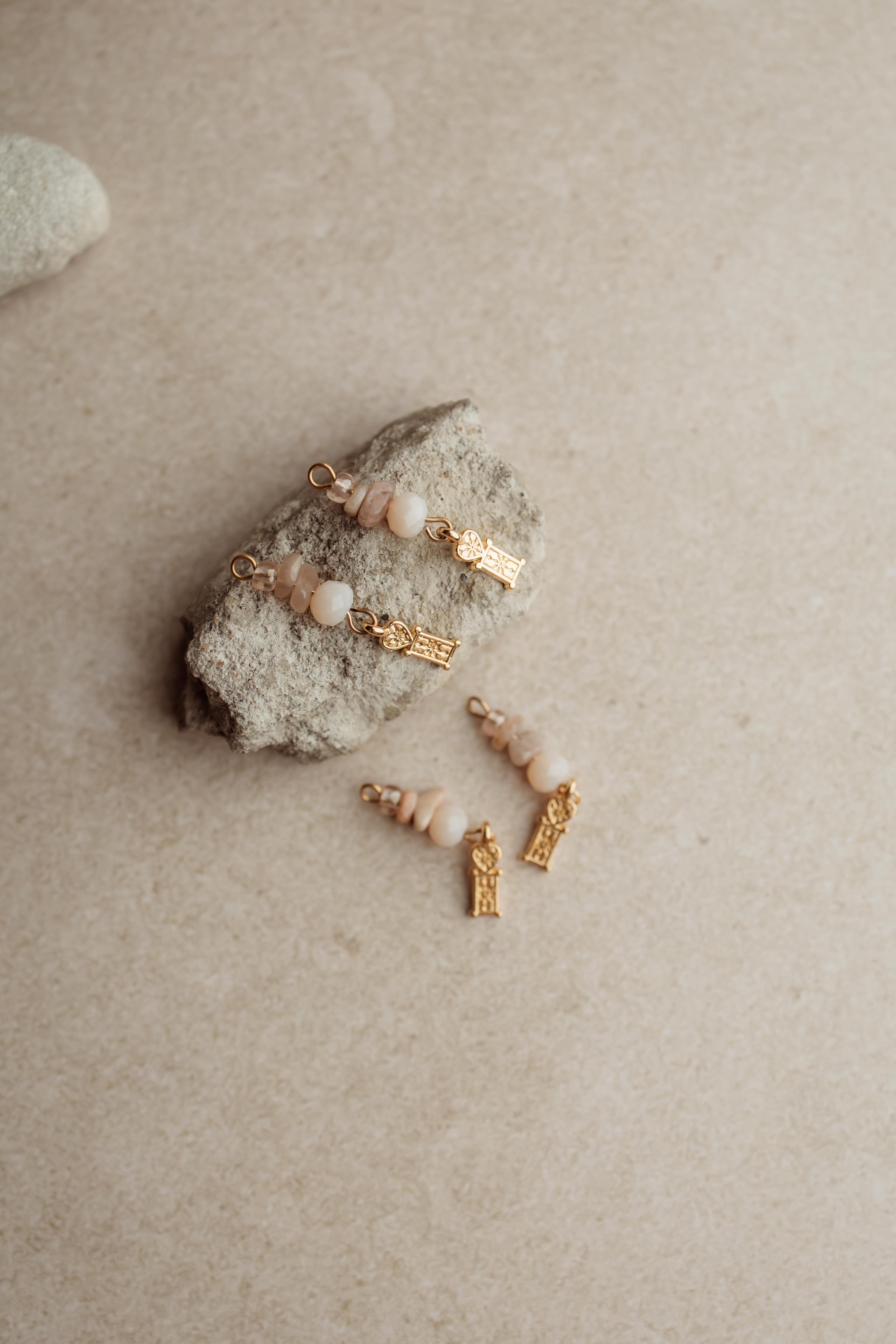 Bedeltjes met gouden details, natuursteen en roze kraaltjes. Mix en match met de oorbellen of ringetjes uit de collectie.